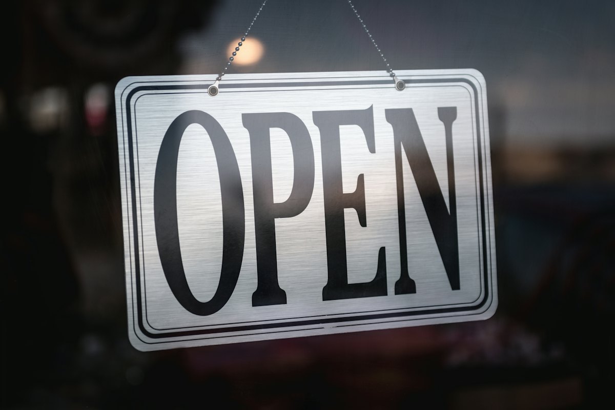 A We're Open sign hanging on the glass door of a small shop